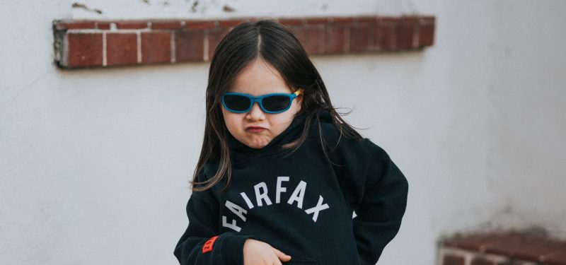 A sassy child in black fairfax sweatshirt and red sun glasses