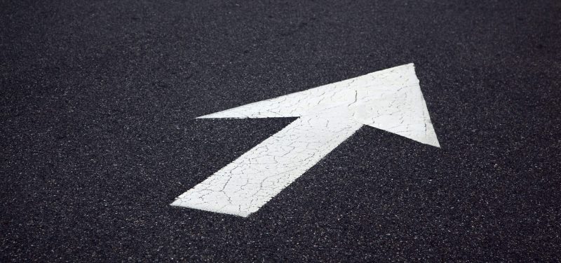 Painted white direction arrow on tarmac